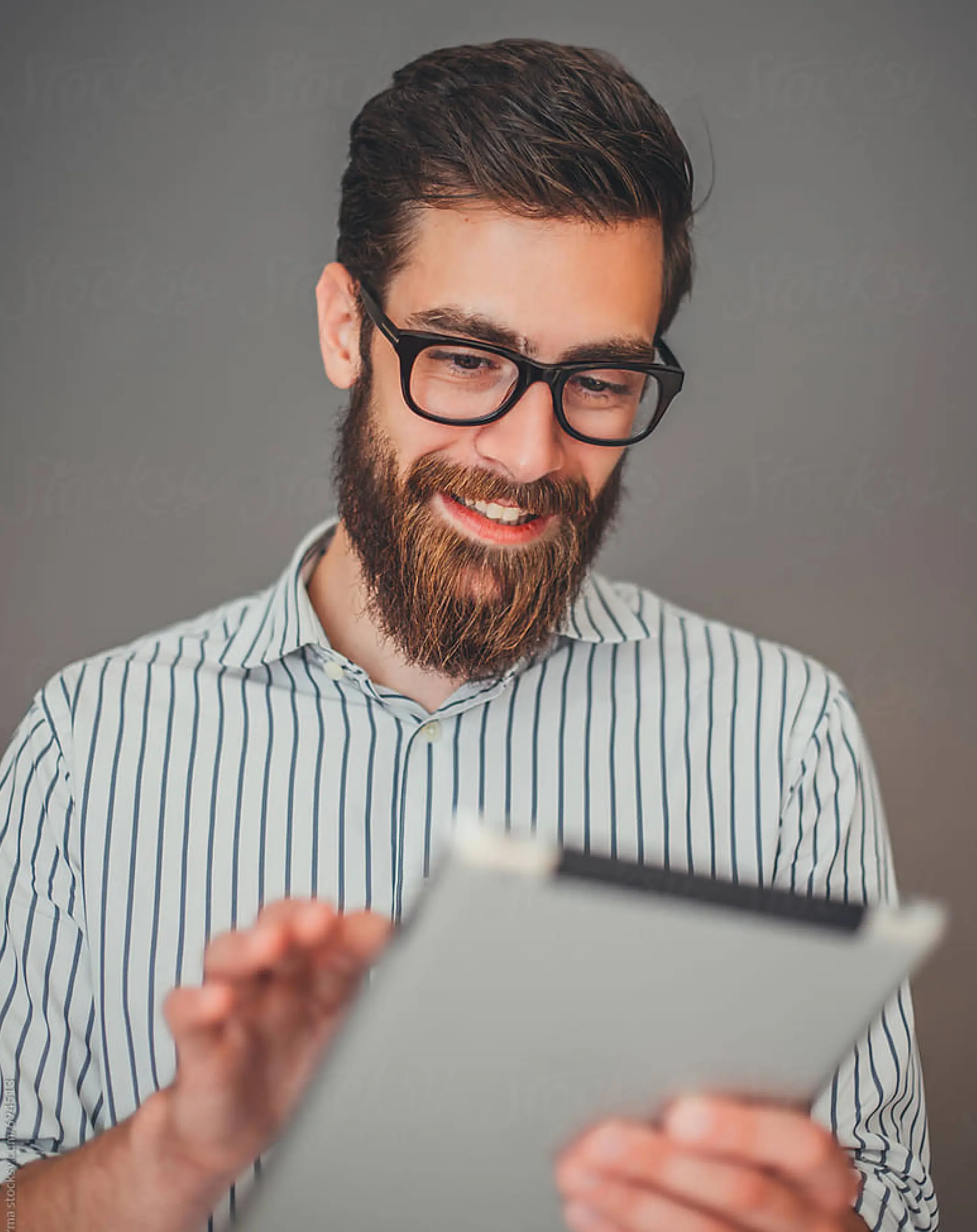 Man smiling, looking at tablet device
