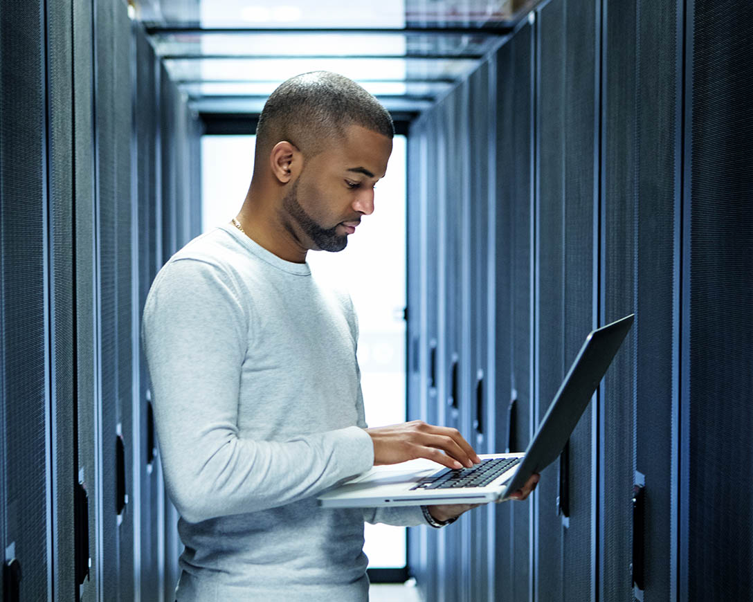 Workload Migration – A male IT technician works on a laptop in a server room