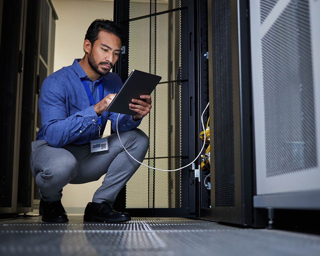Data Mobility – An IT specialistmakes adjustments on a tablet connected to a server