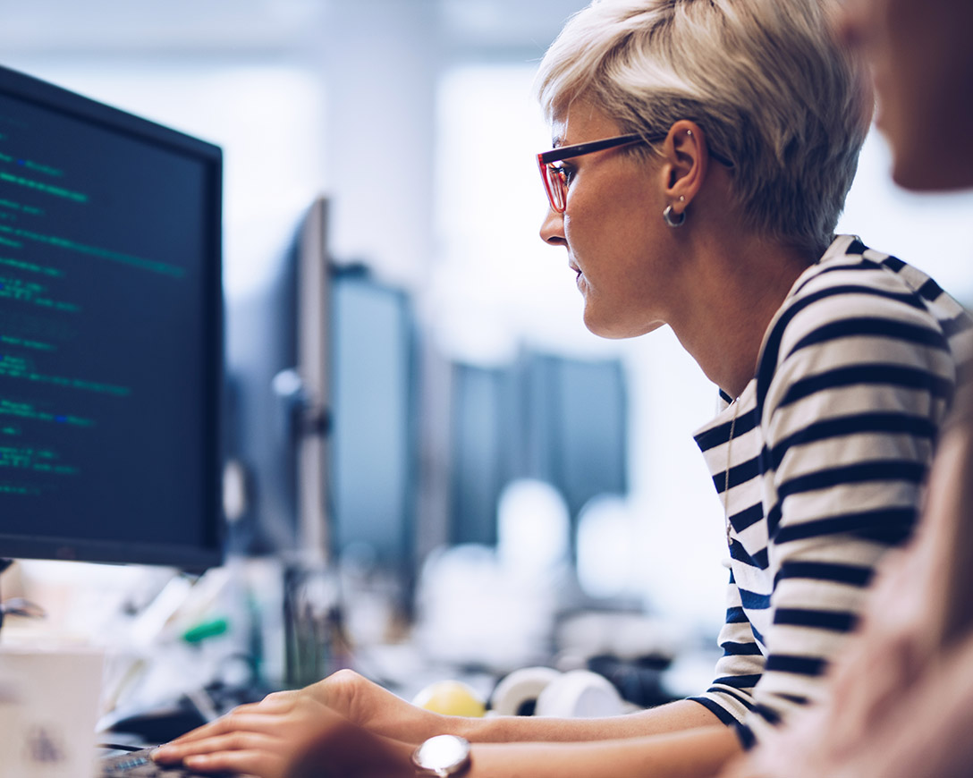 Robust Backup – Side view of a woman working on a desktop PC