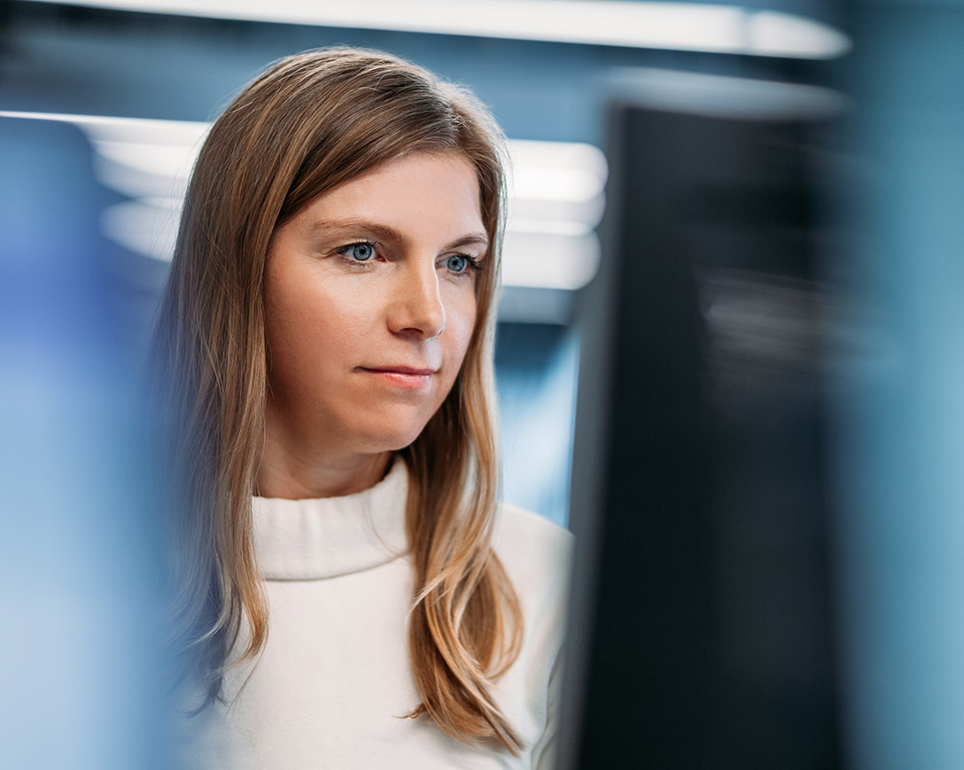 Unified Management - Front view of a woman looking at the monitor of a desktop PC