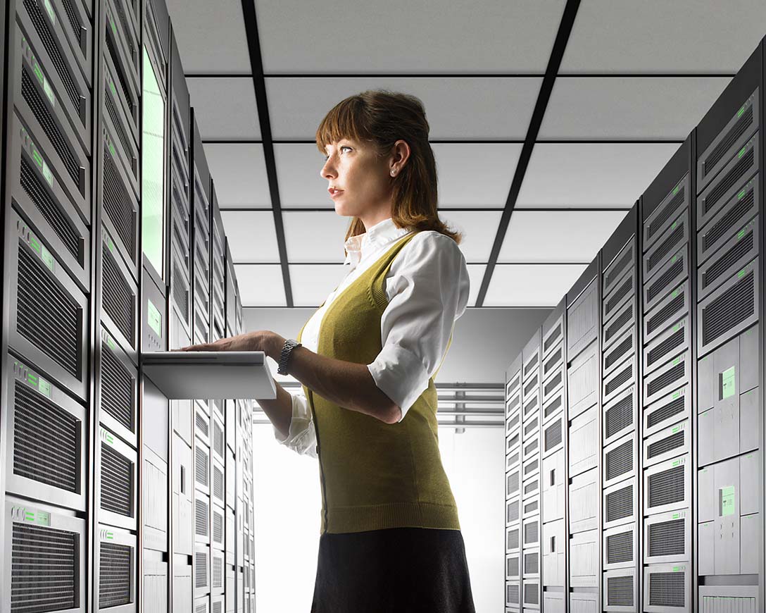 Recover Workloads – A female IT engineer stands at a workstation in a server room