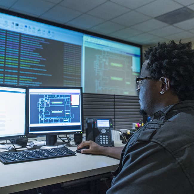 Male IT professional working on dual computer screens at his desk