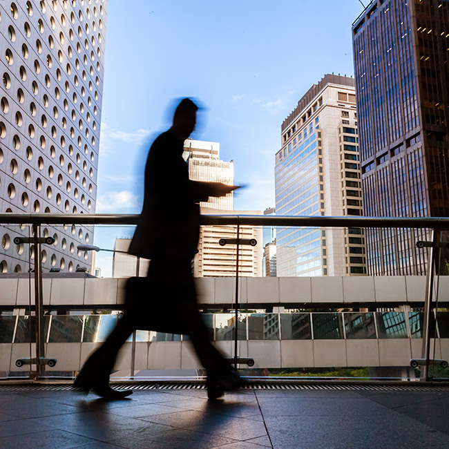 Blurred man carrying briefcase, walking briskly on a walkway