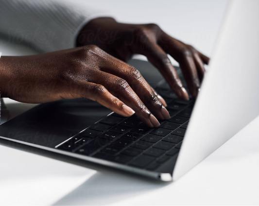 Primo piano delle mani di una donna che scrive sul computer portatile, concentrata e determinata.