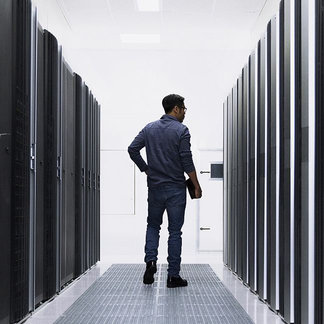 A man strolling through a server room, looking to his right