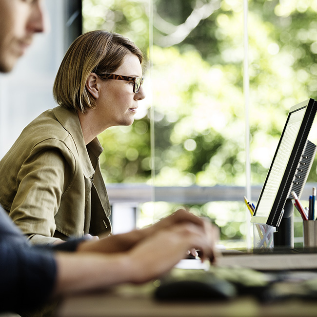 Side view of businesswoman working on computer at desk in office