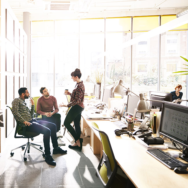 Three people have a conversation in a collaborative workspace