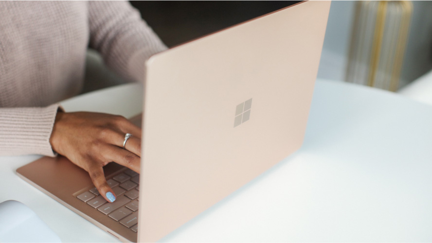 Woman typing on the keyboard of a Microsoft Surface laptop.