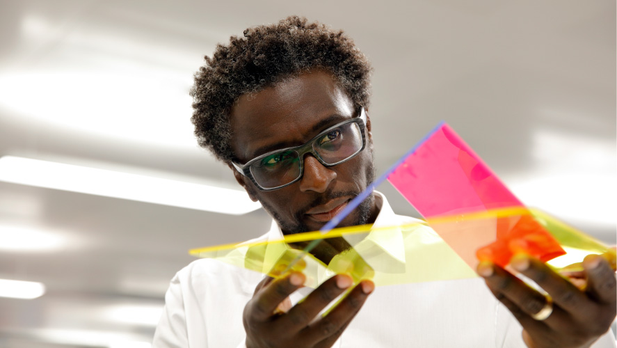 A man in glasses holds a vibrant piece of paper, showcasing a burst of colors.