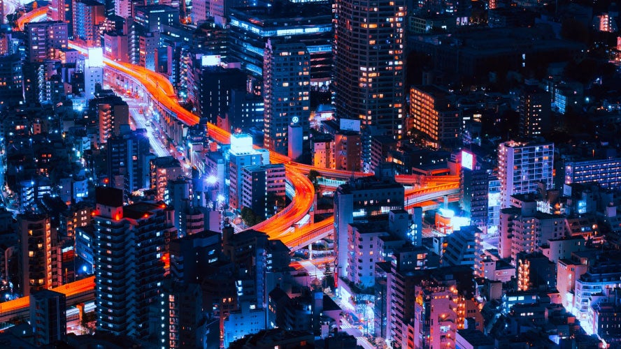 Vue aérienne d'une ville la nuit, avec des feux de circulation illuminés au milieu du paysage urbain.