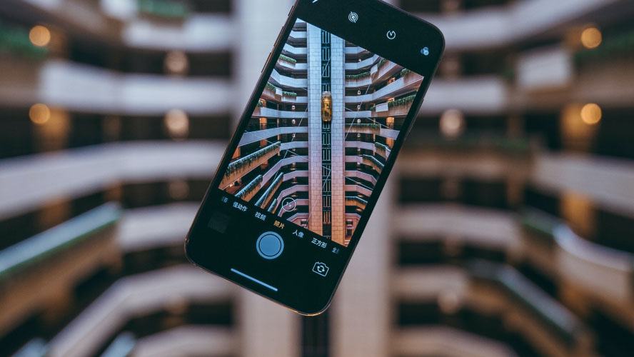 Person using smartphone in front of building.