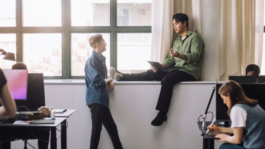 Two professionals discussing work at a table in an office.