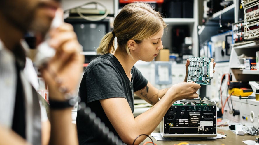 Una donna concentrata sullo schermo del suo computer, che lavora diligentemente in una stanza ben illuminata.