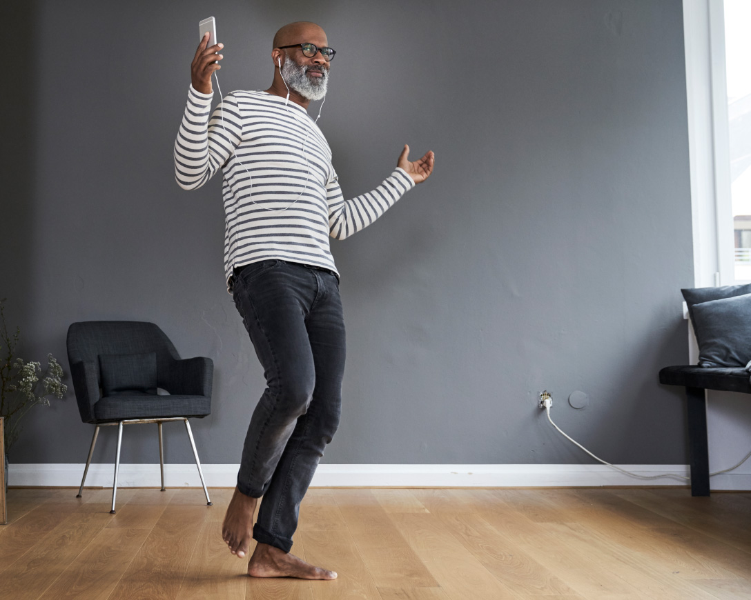 A man with a beard and glasses is joyfully dancing in a room.