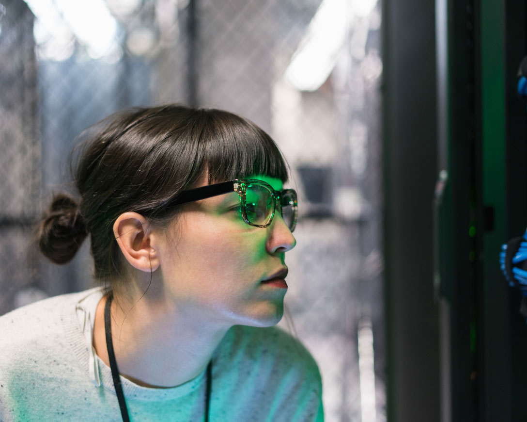 A woman wearing glasses focused on a computer screen, engrossed in her work.