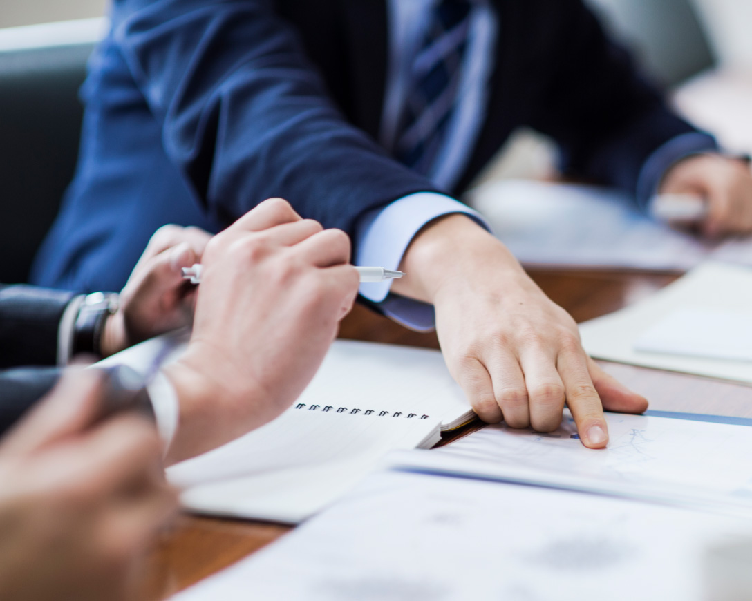 Professionals engaged in a meeting, equipped with papers and pens.