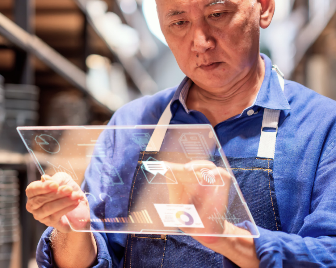 An Asian male engaged in the operation of a digital tablet amidst the surroundings of a warehouse