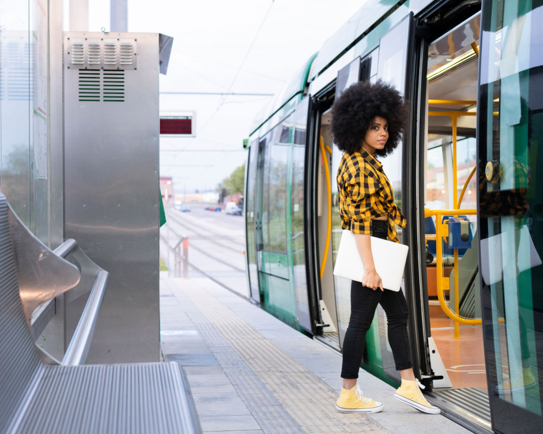 A woman with afro hair stands on a train platform.