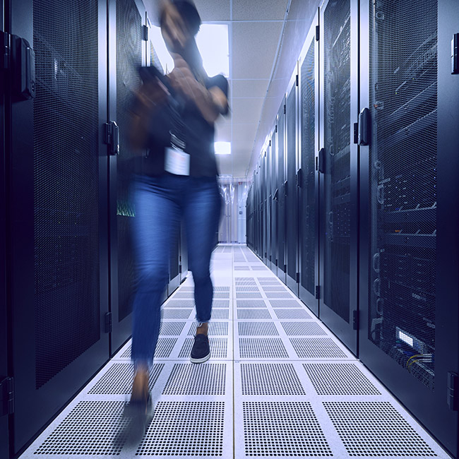 A woman in blurred motion as she walks quickly through a server room