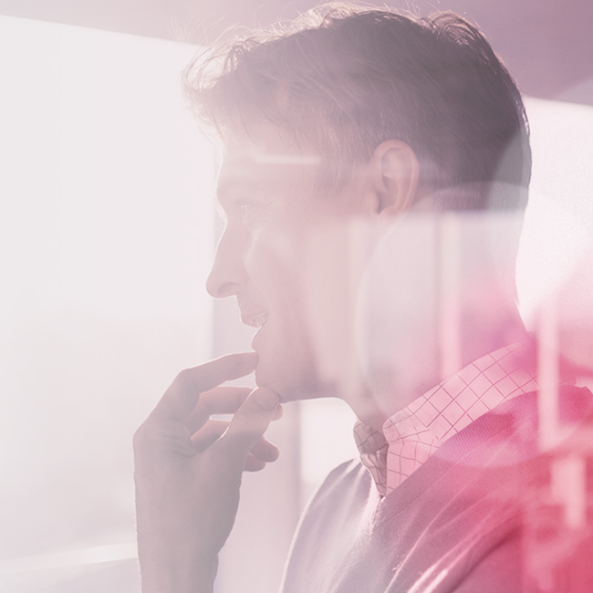 A man gazes out the window against a pink backdrop, lost in thought.