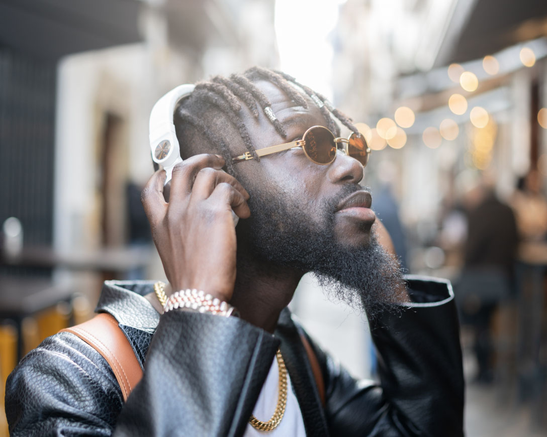 A young African man engrossed in music, wearing headphones, and enjoying the rhythm.