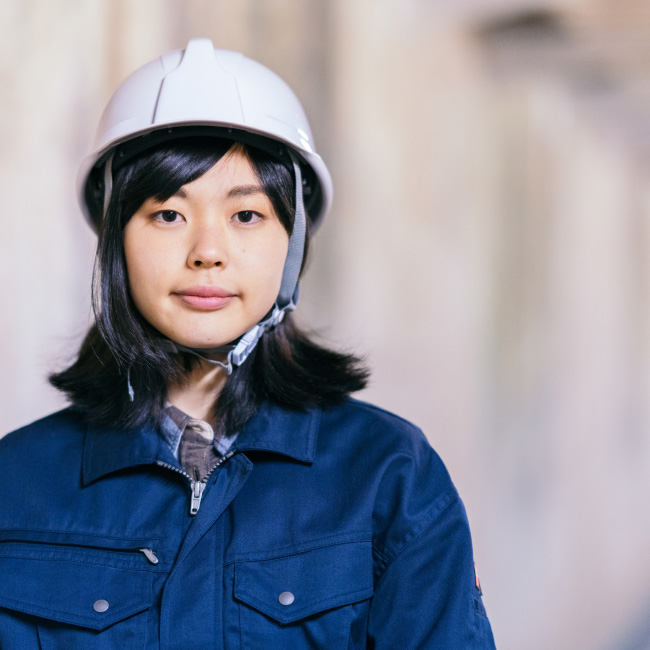 Female worker wearing a hard hat at a construction site.