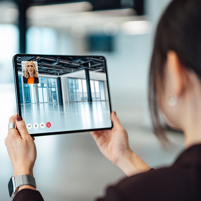 Female property agent showing customer around empty office space through video call on digital tablet